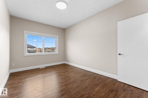 Spacious room featuring wood-finish flooring, neutral-toned walls, and white trim - 16543 132 Street, Edmonton, AB - Indoor Photo Showing Other Room