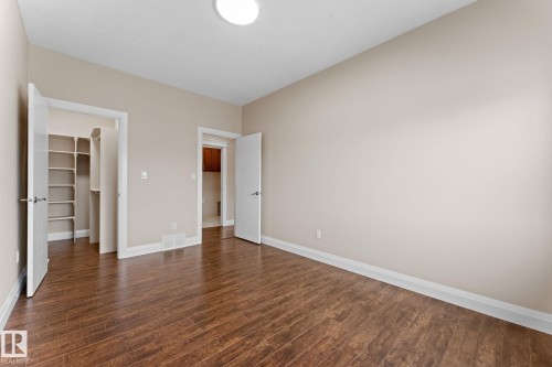 Spacious room featuring wood-finish flooring, light neutral wall tones, white baseboards, and a flush-mount ceiling light - 16543 132 Street, Edmonton, AB - Indoor Photo Showing Other Room
