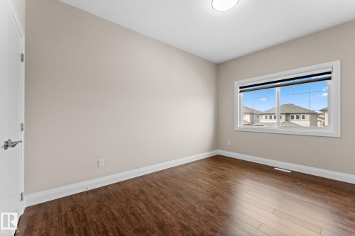 Bright interior space featuring wood-finish flooring, neutral-toned walls, and a large window with white trim - 16543 132 Street, Edmonton, AB - Indoor Photo Showing Other Room