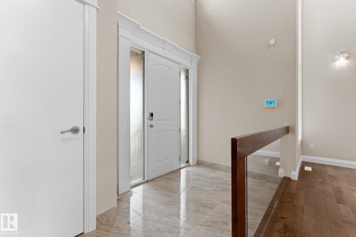 Grand entryway featuring a double-height ceiling, polished tile flooring, and a contemporary entry door with sidelights - 16543 132 Street, Edmonton, AB - Indoor Photo Showing Other Room