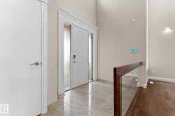 Grand entryway featuring a double-height ceiling, polished tile flooring, and a contemporary entry door with sidelights - 