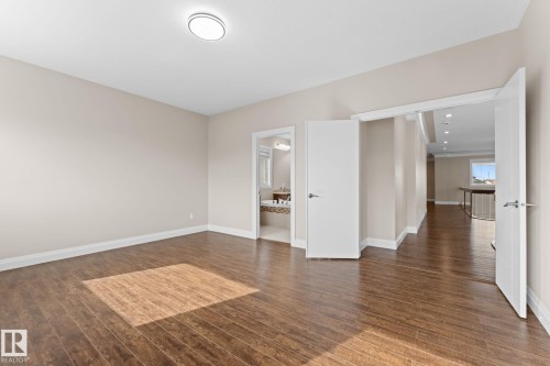 Spacious room featuring wood-finish flooring, neutral-toned walls, and white baseboards - 16543 132 Street, Edmonton, AB - Indoor Photo Showing Other Room
