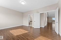 Spacious room featuring wood-finish flooring, neutral-toned walls, and white baseboards - 