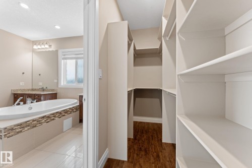 Walk-in closet with extensive built-in shelving, wood-finish flooring, and white trim - 16543 132 Street, Edmonton, AB - Indoor Photo Showing Bathroom