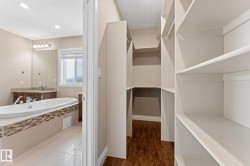 Walk-in closet with extensive built-in shelving, wood-finish flooring, and white trim - 