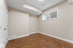 Room featuring wood-finish flooring, neutral wall paint, and white trim throughout - 
