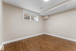 Room featuring wood-finish flooring, neutral wall paint, white baseboards, and a window with horizontal blinds - 