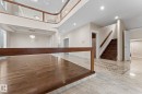 Entryway featuring polished light-toned tile flooring with an intricate inlay design, leading to a hardwood staircase with a dark wood handrail - 16543 132 Street, Edmonton, AB  - Indoor Photo Showing Other Room 