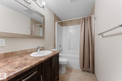 Bathroom featuring a white vanity sink, dark wood-finish cabinetry, a large framed mirror, a tub/shower combination with tile surround, and neutral floor tiling - 