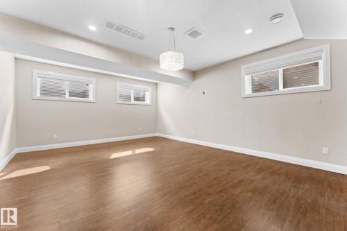 Spacious room featuring rich wood-finish flooring, recessed lighting, and a modern drum pendant fixture - 16543 132 Street, Edmonton, AB - Indoor Photo Showing Other Room