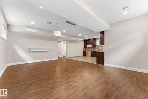Spacious open-concept room featuring wood-finish flooring, recessed lighting, and a contemporary pendant light fixture - 16543 132 Street, Edmonton, AB - Indoor Photo Showing Other Room