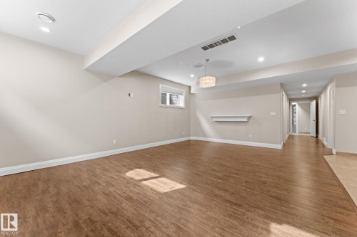 Spacious room featuring wood-finish flooring, recessed lighting, and a contemporary pendant light fixture - 16543 132 Street, Edmonton, AB - Indoor Photo Showing Other Room
