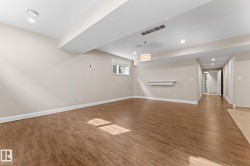 Spacious room featuring wood-finish flooring, recessed lighting, and a contemporary pendant light fixture - 