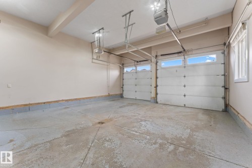 Spacious two-car garage featuring automatic garage door openers, overhead lighting, and two windows providing natural light - 16543 132 Street, Edmonton, AB - Indoor Photo Showing Garage