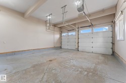 Spacious two-car garage featuring automatic garage door openers, overhead lighting, and two windows providing natural light - 