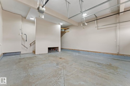 Spacious garage featuring concrete flooring, track lighting, and a built-in staircase - 16543 132 Street, Edmonton, AB - Indoor Photo Showing Garage