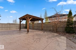 Expansive stamped concrete patio featuring a wood pergola with string lighting - 