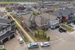 Multi-story residence featuring a two-car garage, stone facade accents, and a front yard with mature trees - 