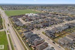 Aerial perspective showcasing a residential development with diverse architectural styles, a grid street pattern, and proximity to open fields - 