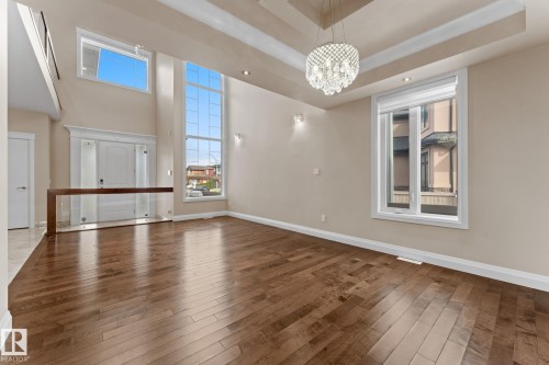 Spacious interior featuring high ceilings with a tiered tray design and a prominent crystal chandelier - 16543 132 Street, Edmonton, AB - Indoor Photo Showing Other Room