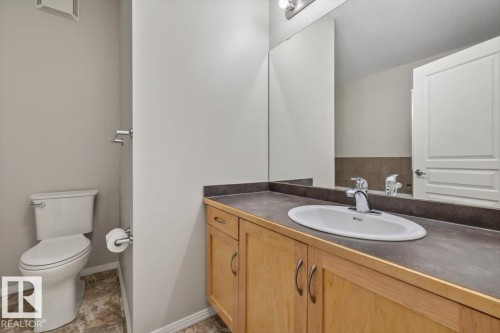 Bathroom featuring a light wood-finish vanity with an integrated sink, dark countertop, and chrome faucet - 228 10531 117 Street, Edmonton, AB - Indoor Photo Showing Bathroom