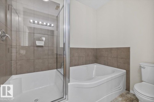 Bathroom featuring a corner soaking tub, a stand-up shower with a glass enclosure, and a tiled shower surround - 228 10531 117 Street, Edmonton, AB - Indoor Photo Showing Bathroom
