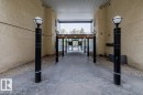 Covered outdoor walkway featuring a textured stucco exterior, corrugated metal ceiling, and a concrete pathway - 228 10531 117 Street, Edmonton, AB  - Indoor Photo Showing Other Room 