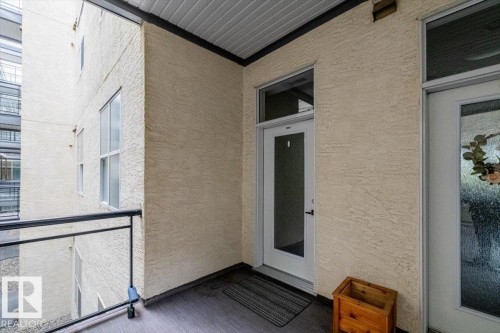 Private balcony entrance featuring wood-finish flooring and a black metal railing - 228 10531 117 Street, Edmonton, AB - Outdoor With Exterior