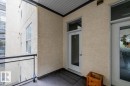 Private balcony entrance featuring wood-finish flooring and a black metal railing - 228 10531 117 Street, Edmonton, AB  - Outdoor With Exterior 