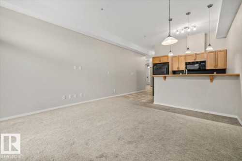 Open-concept living area with neutral carpeting and light wall tones - 228 10531 117 Street, Edmonton, AB - Indoor Photo Showing Kitchen