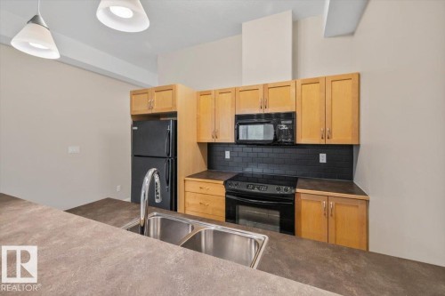 Kitchen featuring a double basin stainless steel sink, black subway tile backsplash, and light wood-finish cabinetry - 228 10531 117 Street, Edmonton, AB - Indoor Photo Showing Kitchen With Double Sink