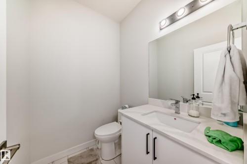 The bathroom features a vanity with a white countertop and an integrated sink, a large mirror, and a modern light fixture - 4509 170A Avenue, Edmonton, AB - Indoor Photo Showing Bathroom