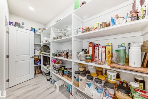 Spacious pantry featuring extensive white shelving and light-colored flooring, providing ample storage - 4509 170A Avenue, Edmonton, AB - Indoor With Storage