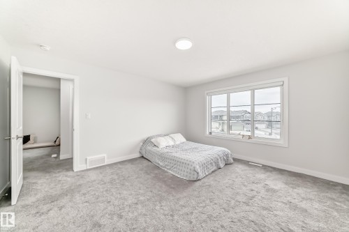 This bright room features light grey carpeting, white walls, and a large window with views of the surrounding neighborhood - 4509 170A Avenue, Edmonton, AB - Indoor Photo Showing Bedroom