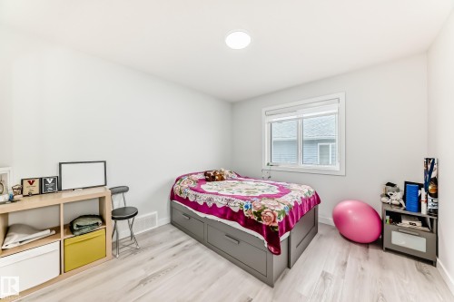 This room features light-colored walls, light wood-look flooring, and a window with white blinds - 4509 170A Avenue, Edmonton, AB - Indoor Photo Showing Bedroom