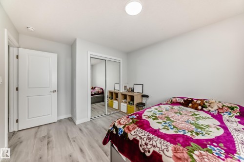 This room features light-toned flooring, a white paneled door, and a mirrored closet - 4509 170A Avenue, Edmonton, AB - Indoor Photo Showing Bedroom