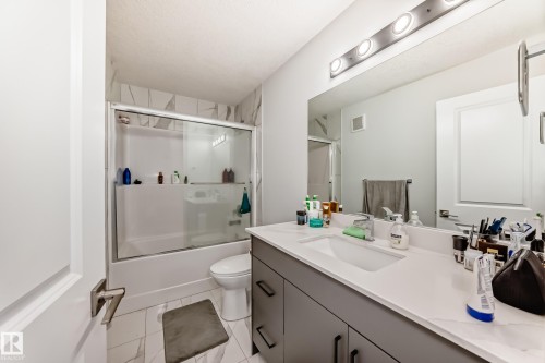 Bathroom featuring a vanity with a white countertop and a rectangular sink, a toilet, and a bathtub with a sliding glass door - 4509 170A Avenue, Edmonton, AB - Indoor Photo Showing Bathroom