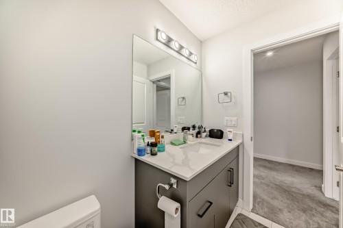The bathroom features a vanity with a white countertop and a rectangular sink, complemented by a large mirror and modern light fixture - 4509 170A Avenue, Edmonton, AB - Indoor Photo Showing Bathroom