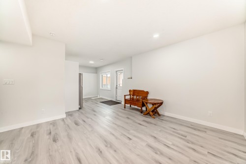 The property features light-colored plank flooring and white walls throughout the open area - 4509 170A Avenue, Edmonton, AB - Indoor Photo Showing Other Room