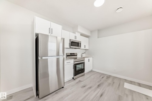 Kitchen featuring white cabinetry, stainless steel appliances, and wood-look flooring - 4509 170A Avenue, Edmonton, AB - Indoor Photo Showing Kitchen With Stainless Steel Kitchen