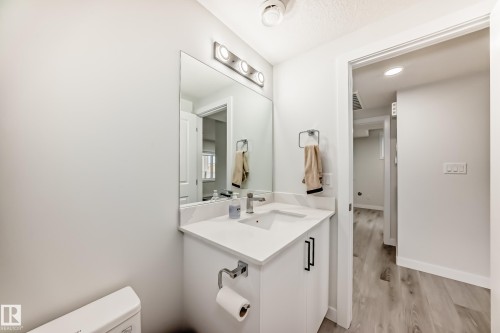 Bathroom featuring a vanity with a white countertop, a mirror with overhead lighting, and light-colored flooring - 4509 170A Avenue, Edmonton, AB - Indoor Photo Showing Bathroom