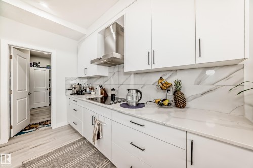 The kitchen features white cabinetry, a stainless steel range hood, and a white countertop with a matching backsplash - 4509 170A Avenue, Edmonton, AB - Indoor Photo Showing Kitchen