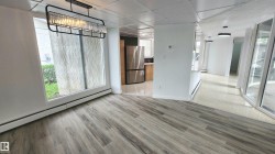 Spacious room with wood-finish flooring, a contemporary linear chandelier, and expansive windows - 