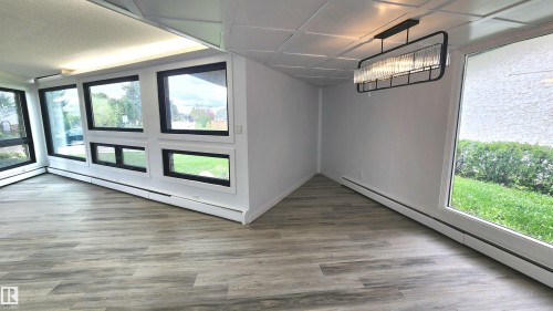 Contemporary lighting fixture illuminating a space with wood-finish flooring - 9535 147 Avenue, Edmonton, AB - Indoor Photo Showing Other Room