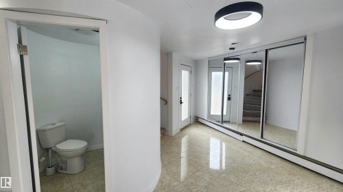 Entryway featuring tile flooring, sliding mirror wardrobe doors, and a contemporary ceiling fixture - 9535 147 Avenue, Edmonton, AB - Indoor Photo Showing Bathroom
