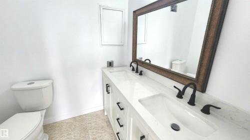 Dual vanity with white cabinetry and dark hardware, featuring integrated rectangular sinks and matte black faucets - 9535 147 Avenue, Edmonton, AB - Indoor Photo Showing Bathroom