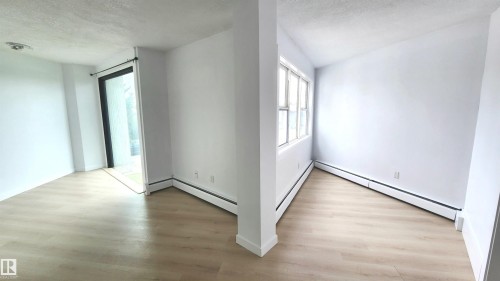 Bright interior space featuring light wood-finish flooring, white baseboard trim, and a full-light glass door - 9535 147 Avenue, Edmonton, AB - Indoor Photo Showing Other Room