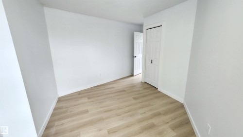 Room featuring light wood-finish flooring, white walls, and a white six-panel door - 9535 147 Avenue, Edmonton, AB - Indoor Photo Showing Other Room
