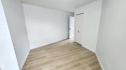 Room featuring light wood-finish flooring, white walls, and a white six-panel door - 