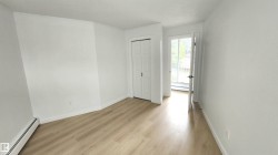Bright interior space featuring light wood-finish flooring, white walls, and a bi-fold closet door - 